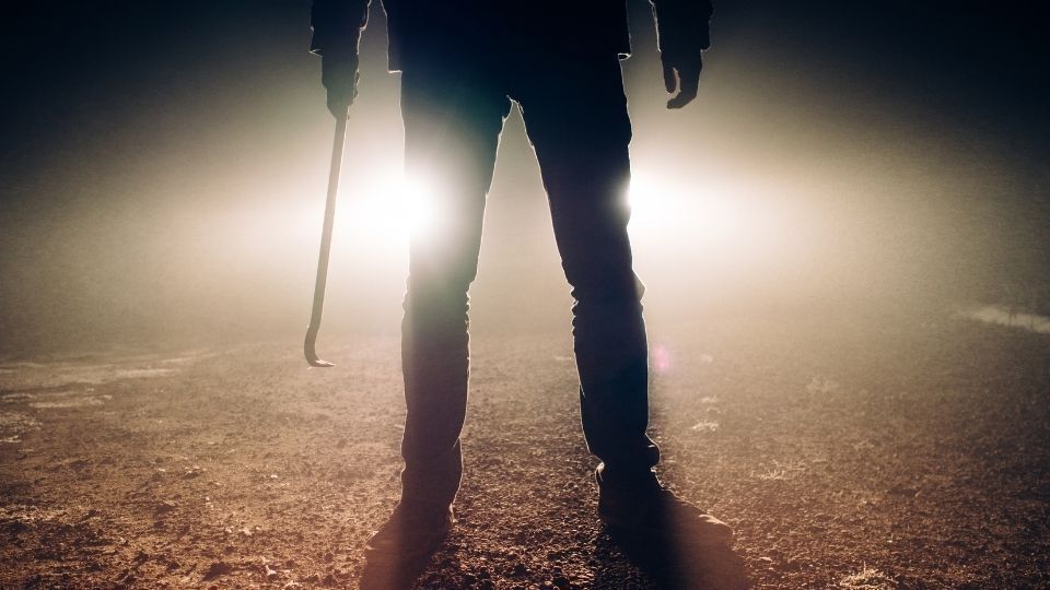 Burglar standing outside at night holding a crowbar. Alarm system