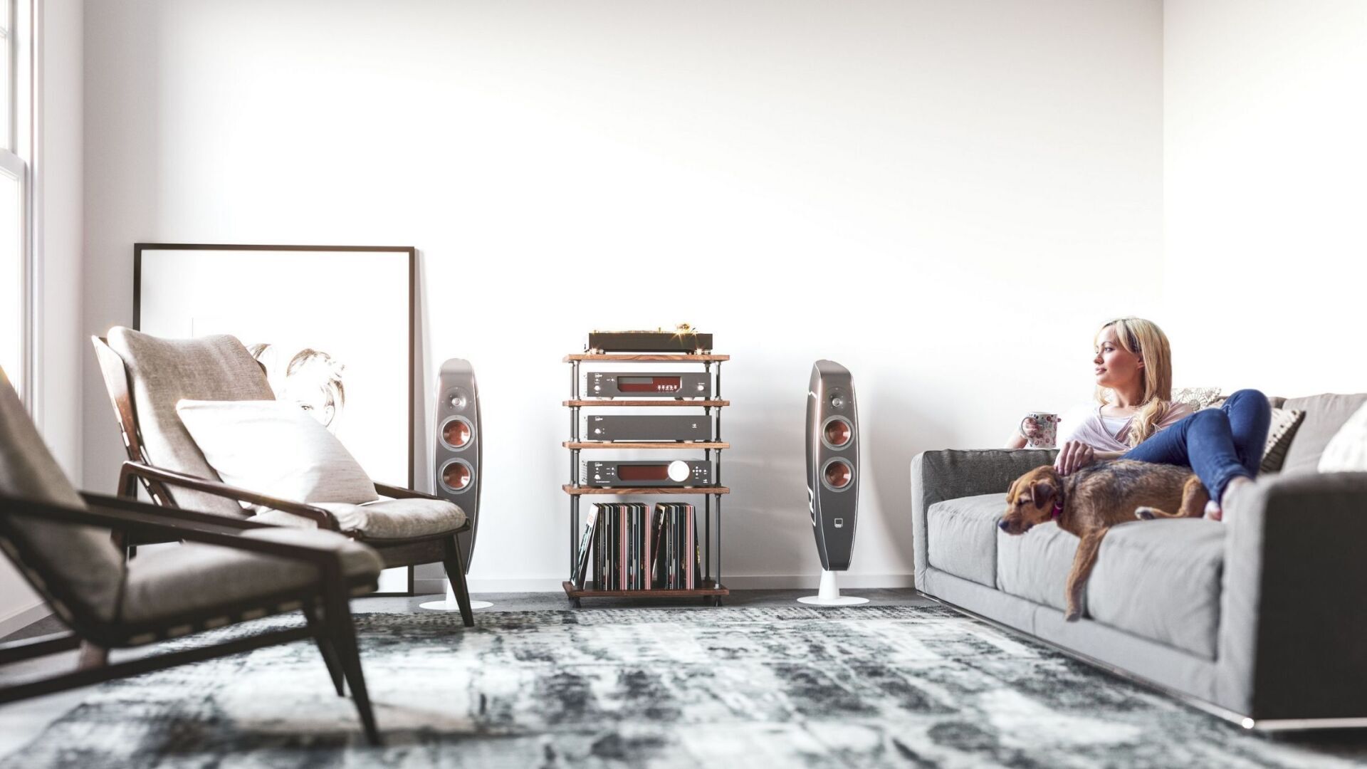 Woman sitting on couch with dog listening to music. Hi-Fi floor speakers