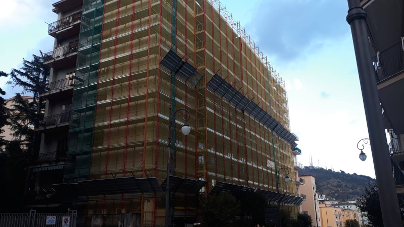 Un alto edificio avvolto da impalcature e reti di protezione