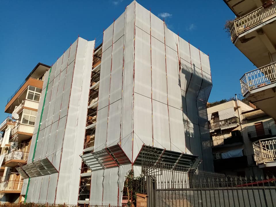 Un alto edificio avvolto in una rete da cantiere bianca