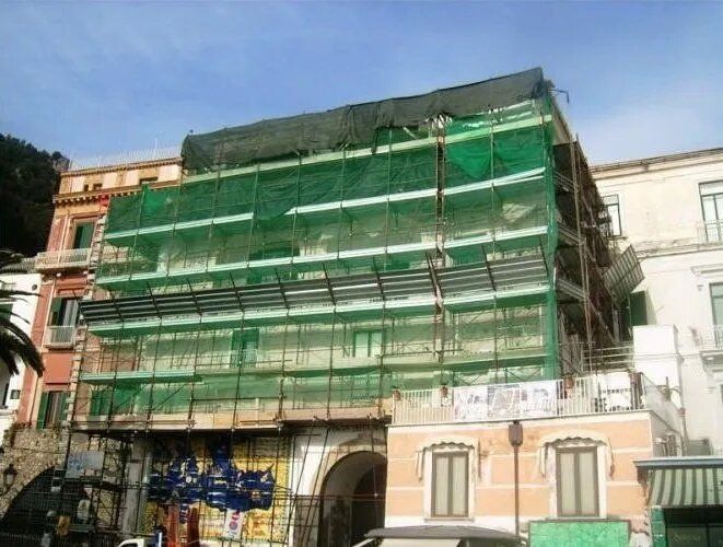 Edificio ricoperto da una rete di ponteggi verde durante i lavori di costruzione o ristrutturazione