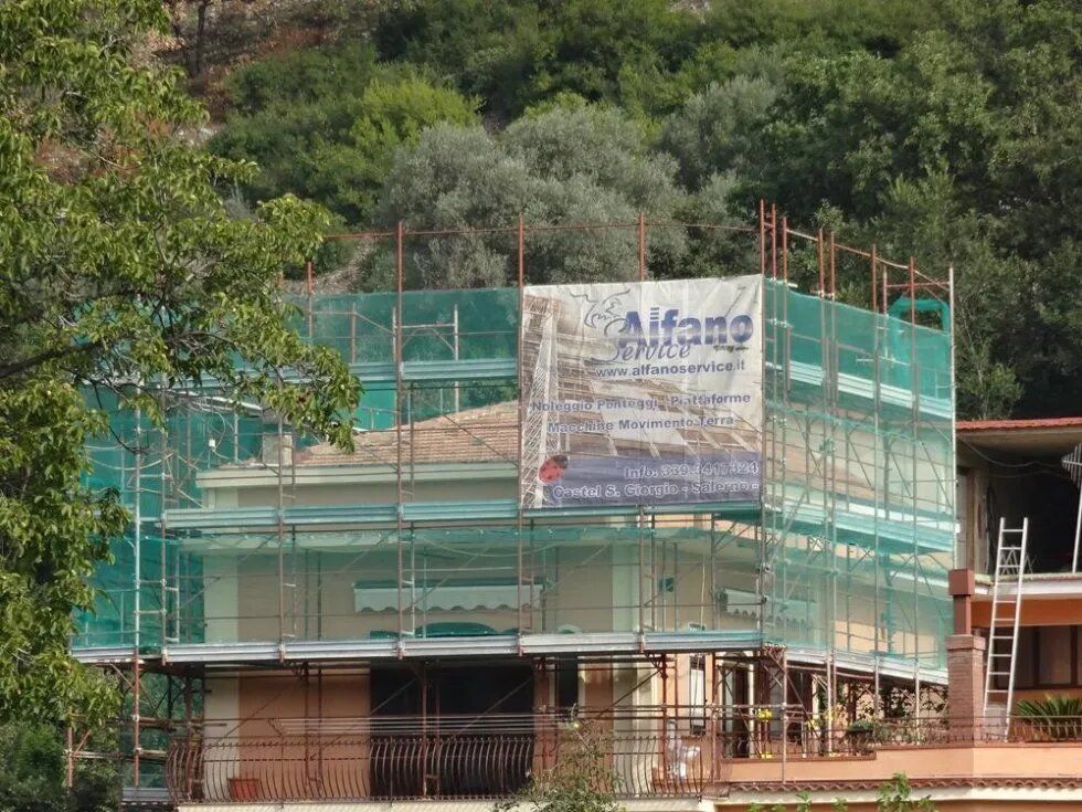 Casa in costruzione avvolta da impalcature verdi