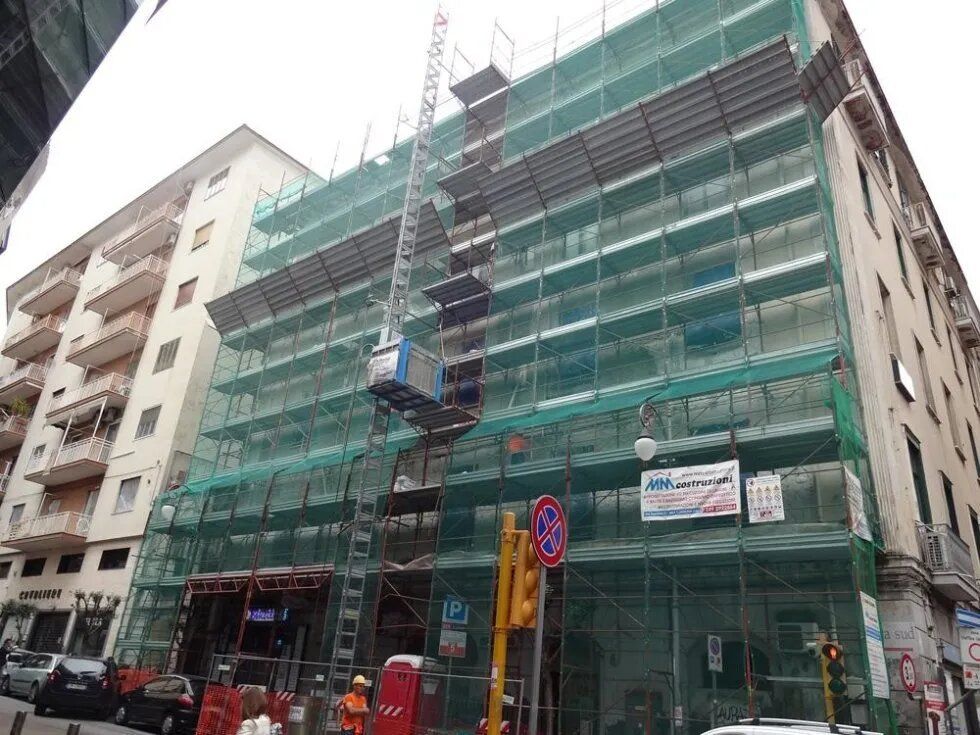 Edificio avvolto da una rete di impalcature verde
