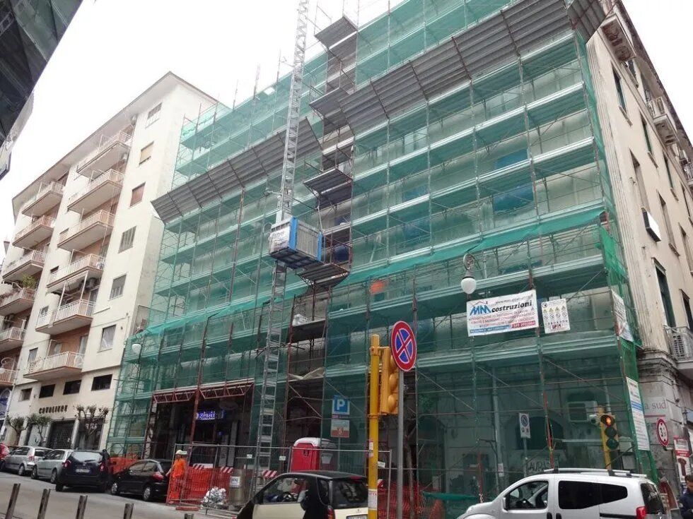Edificio residenziale in fase di ristrutturazione, con impalcature e reti di sicurezza verdi