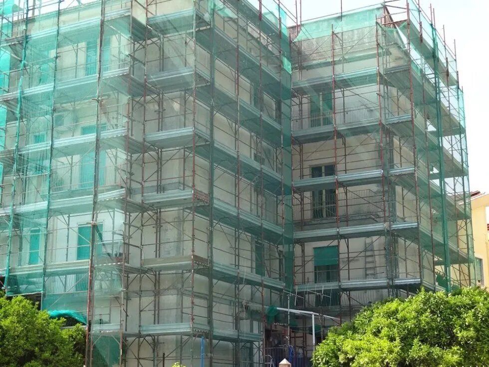 Edificio con impalcature ricoperto da una rete da cantiere verde