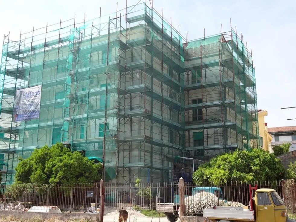 Edificio in costruzione avvolto in una rete di impalcature verdi