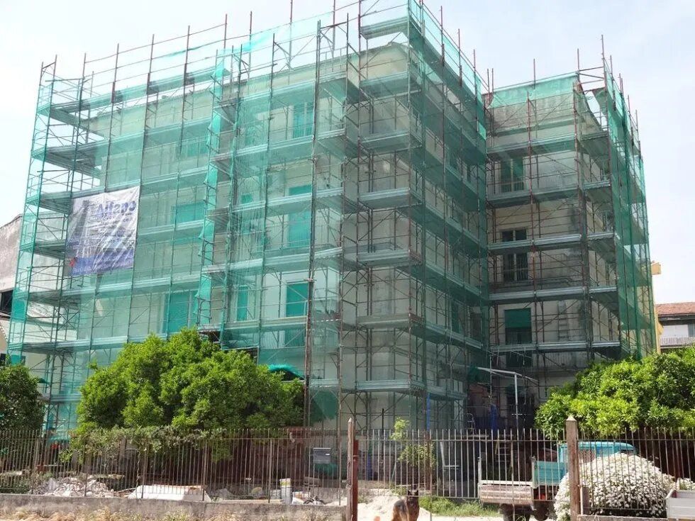 Edificio in costruzione avvolto da reti di sicurezza verdi