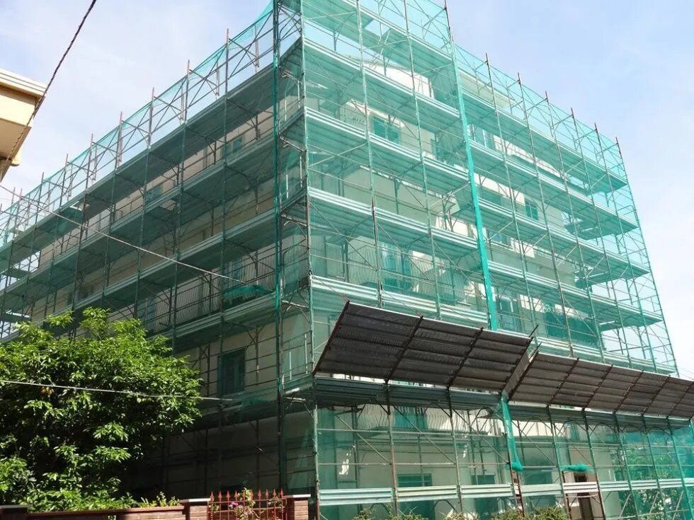 Edificio in costruzione con struttura a rete verde, impalcature