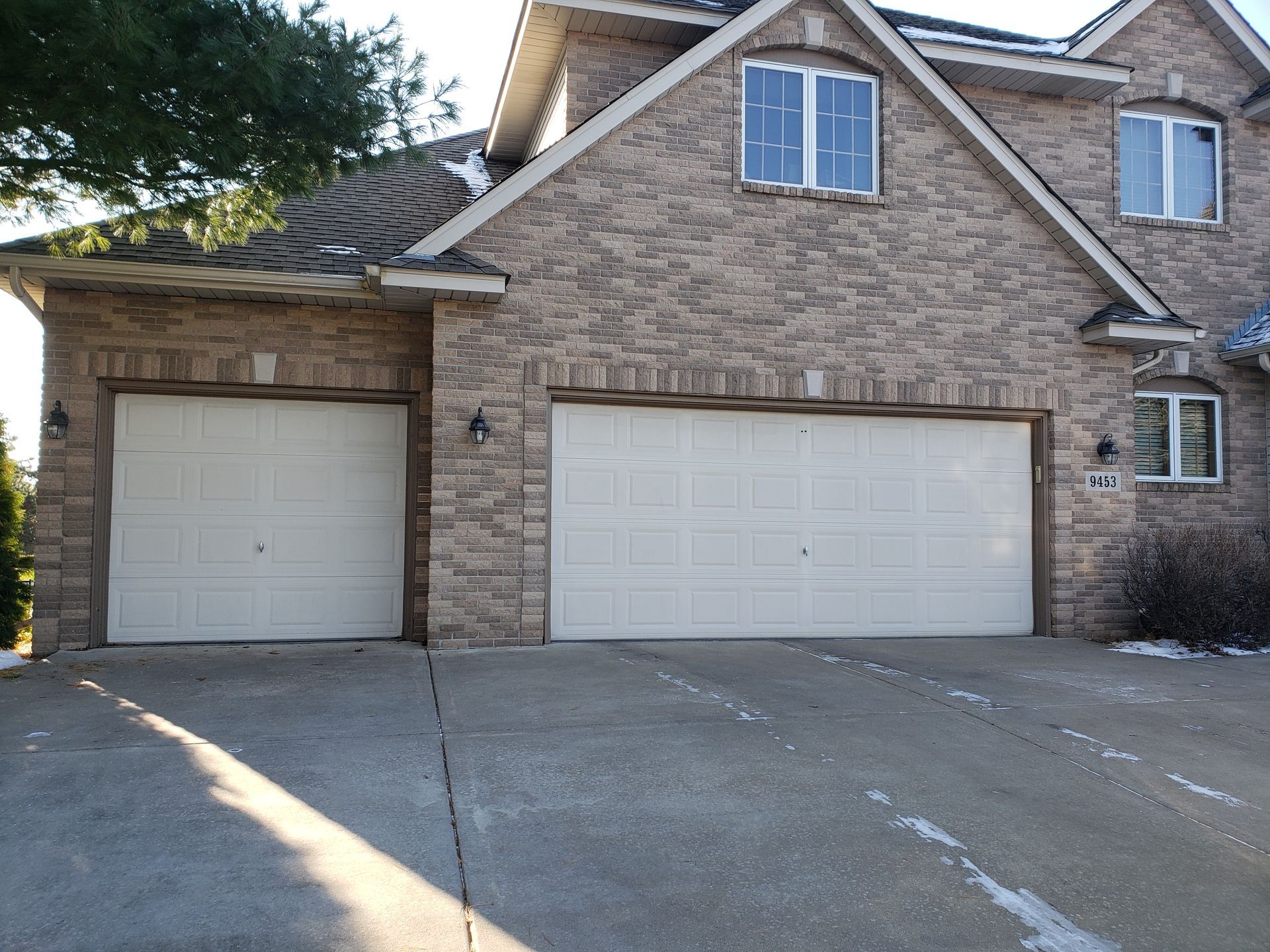 Brick suburban house with a two-car garage and concrete driveway in daylight