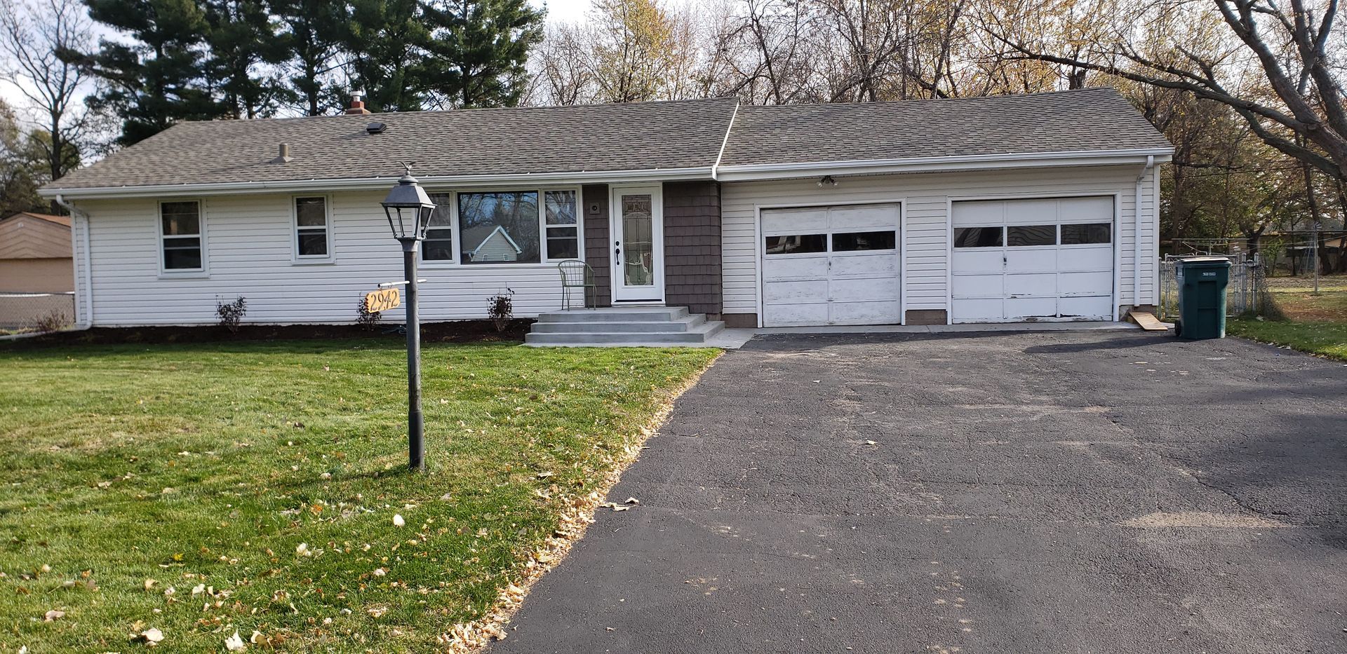 Single-story white house with attached two-car garage, front lawn, and asphalt driveway