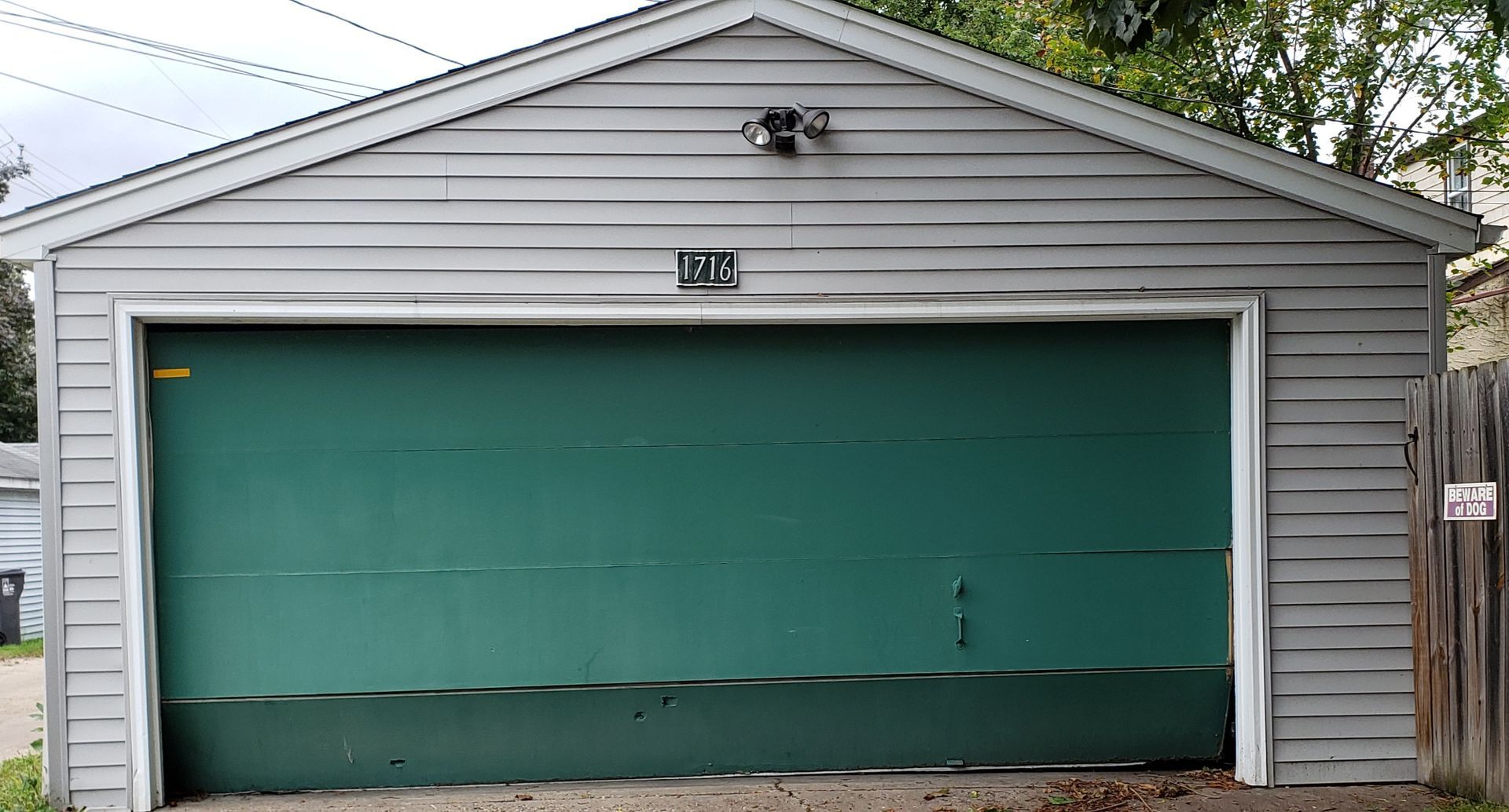 Gray garage with a teal door and a small house number above it