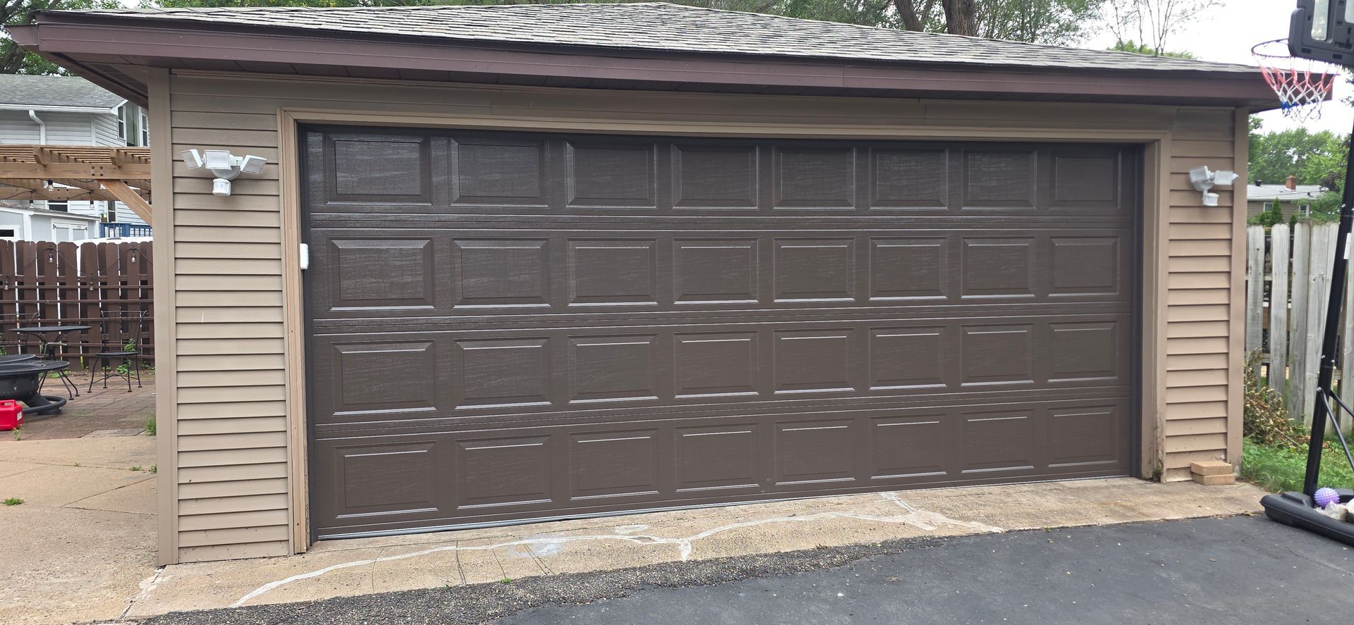 Brown double garage door on a beige house exterior