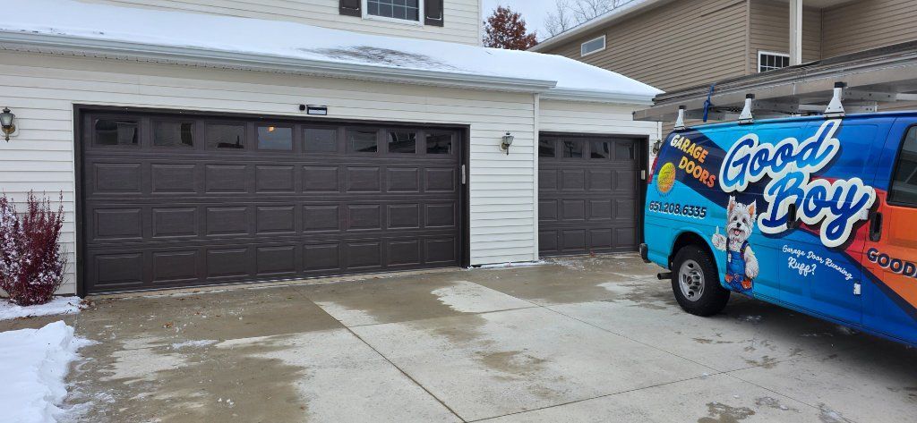 Snowy suburban driveway with a dark garage and a blue Good Humor truck parked outside