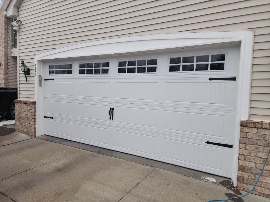White double garage door with small windows on a beige house exterior