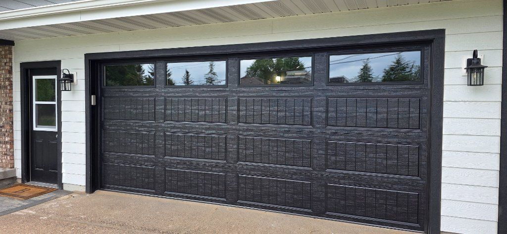 Black double garage door on a white brick house exterior