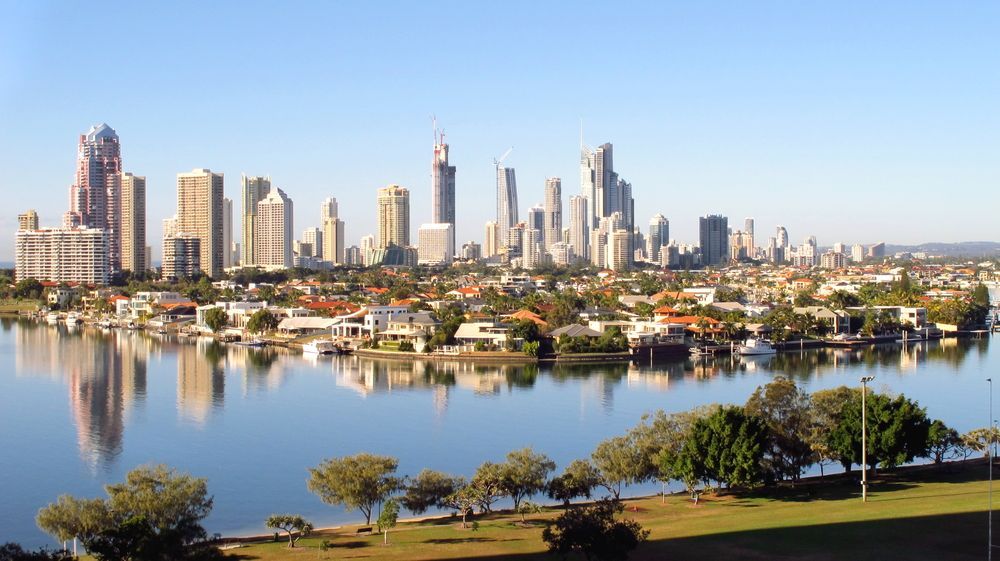 A City Skyline Is Reflected In A Body Of Water — Queensland Lawyers Cairns In Gold Coast, QLD