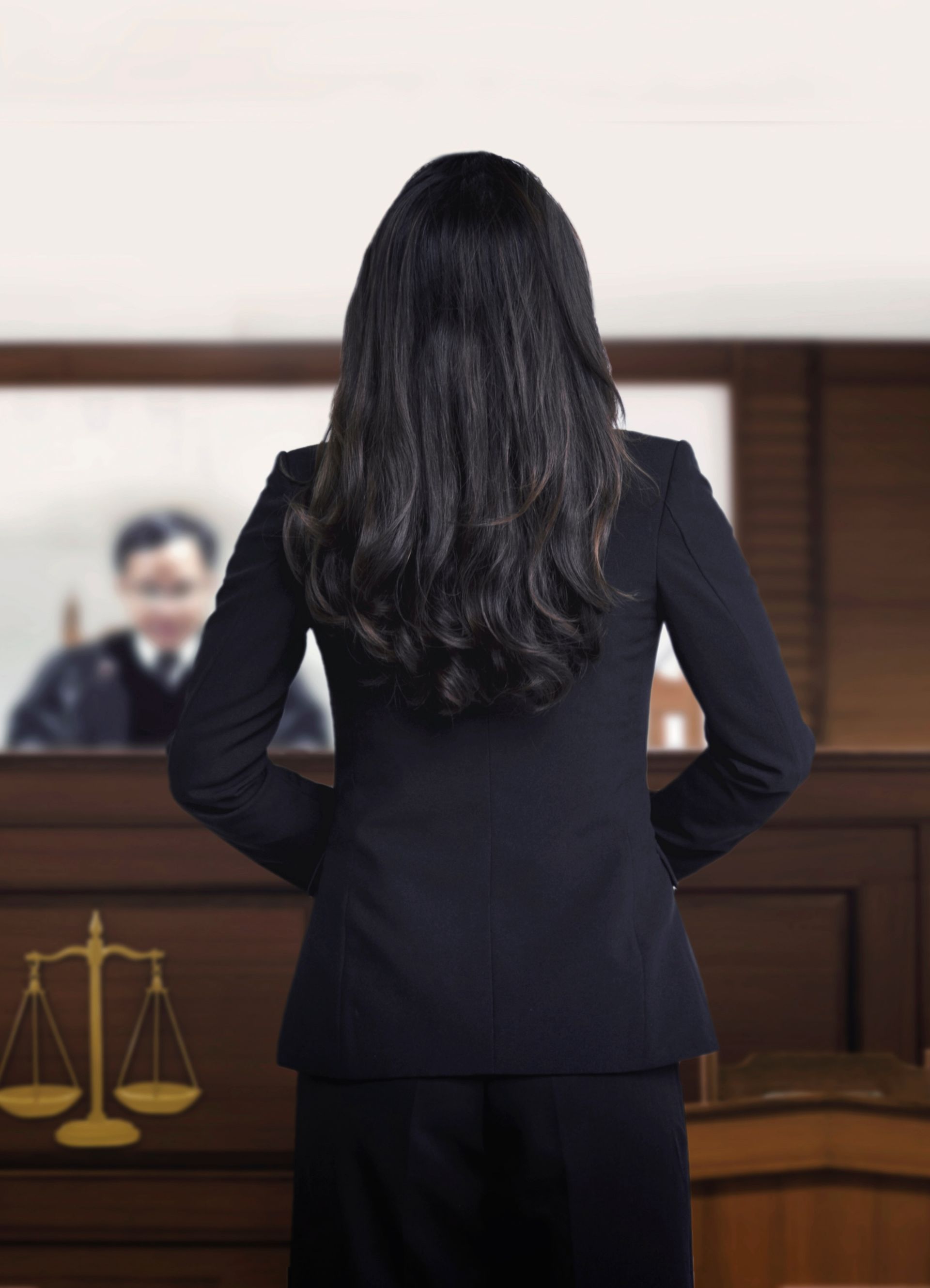 Woman In Black Suit Standing At A Courtroom Lectern, Seen From Behind - Queensland Lawyers in Cairns QLD