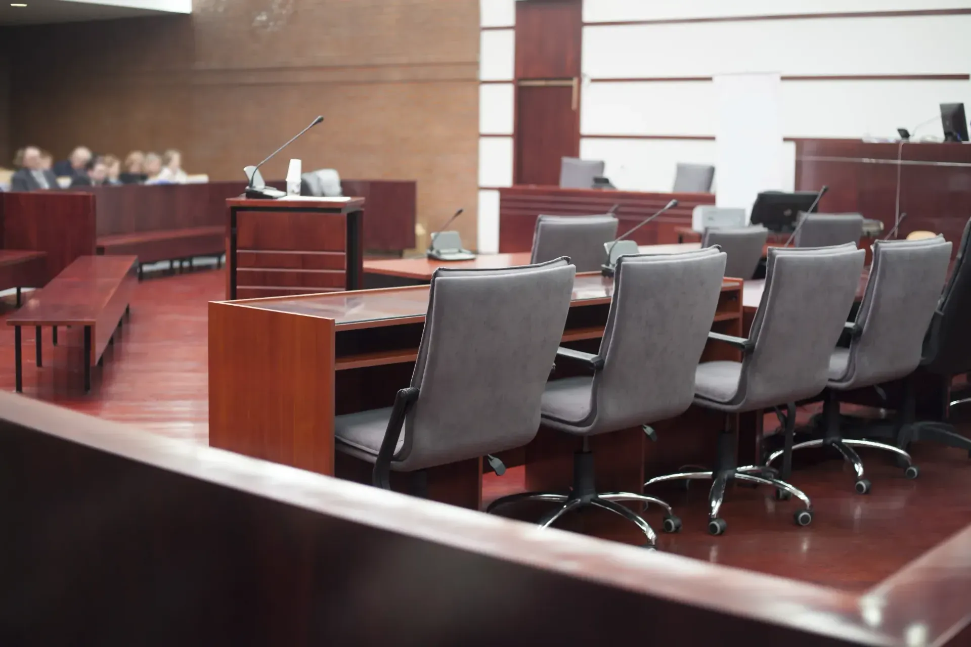 Empty Courtroom With Rows Of Gray Chairs, Wooden Benches, And Counsel Tables Under Bright Lights - Queensland Lawyers in Cairns QLD
