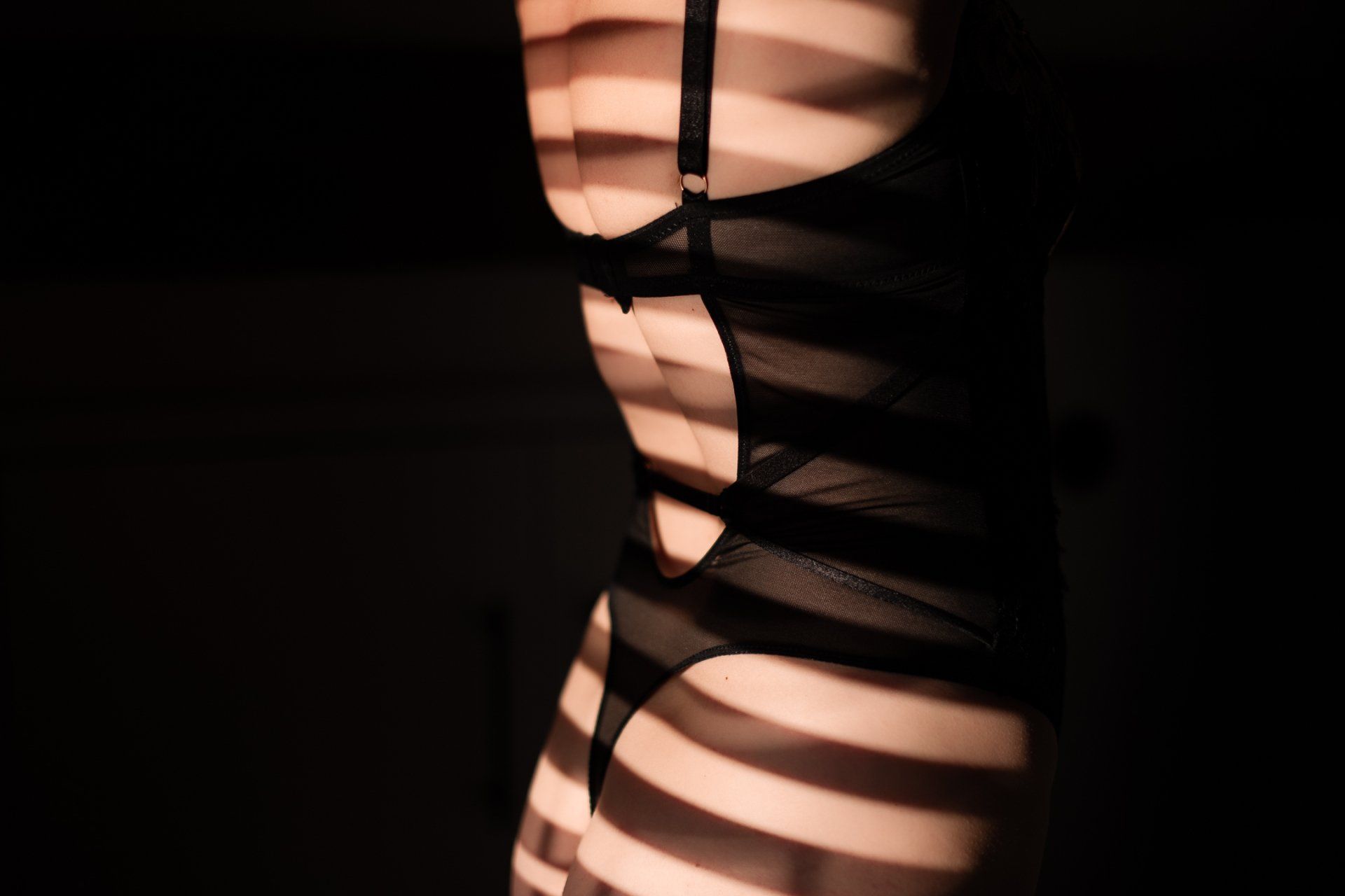 Schaduwfiguur in zwarte lingerie met een licht gestreept patroon.