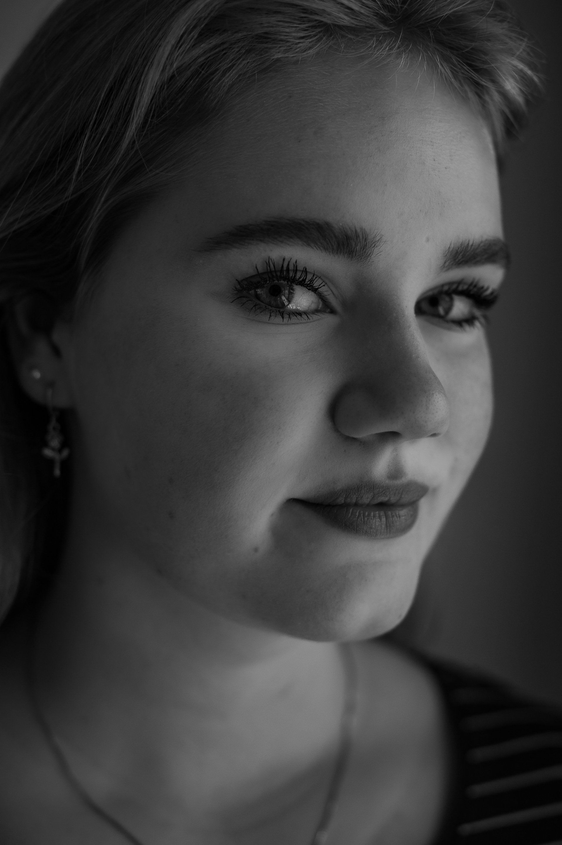Vrouw met een lichte huid, kijkt iets opzij, draagt make-up en een gestreept topje. Zwart-witfoto.