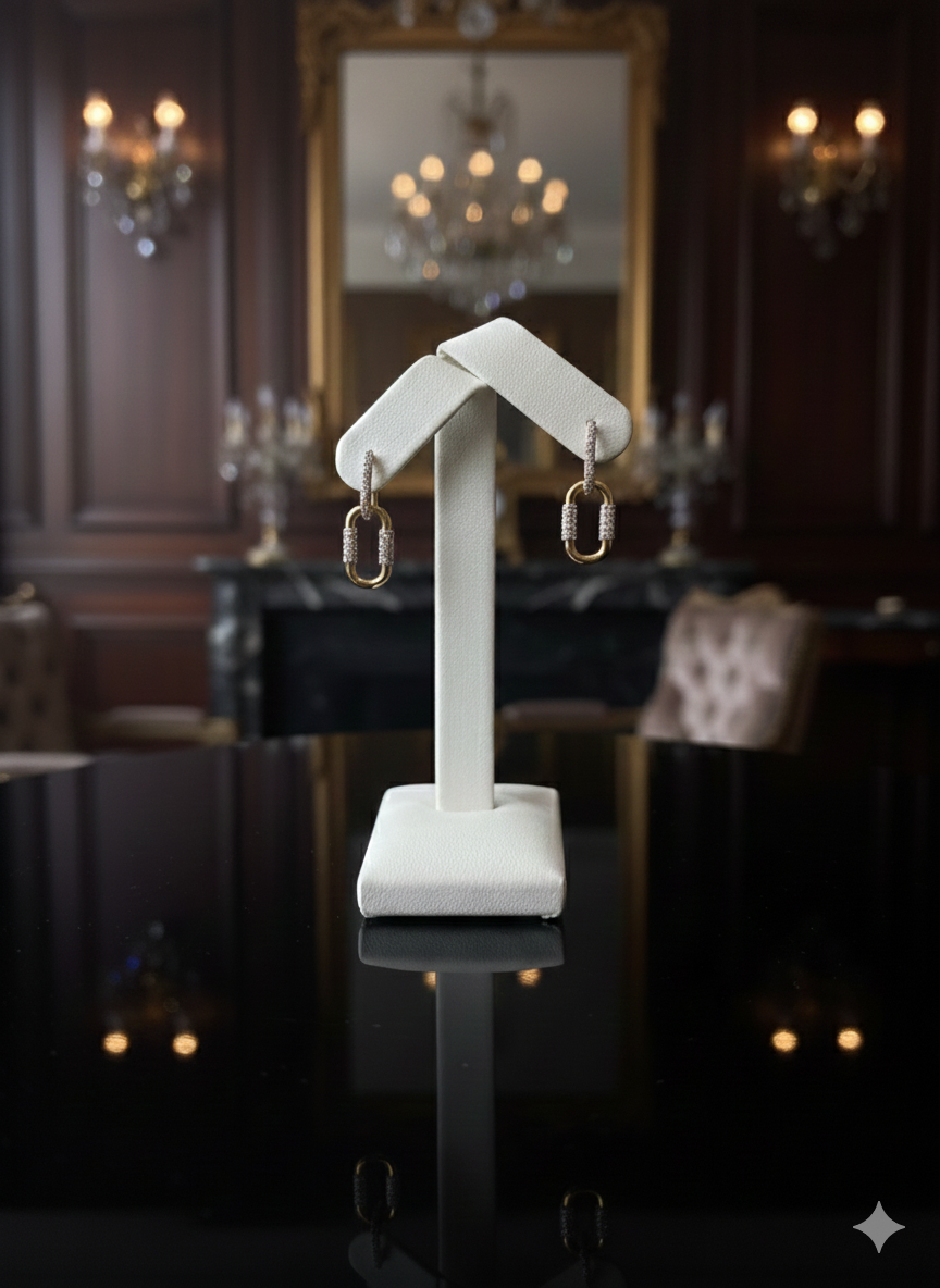 Earrings on display stand in a room with a large mirror and chandelier.