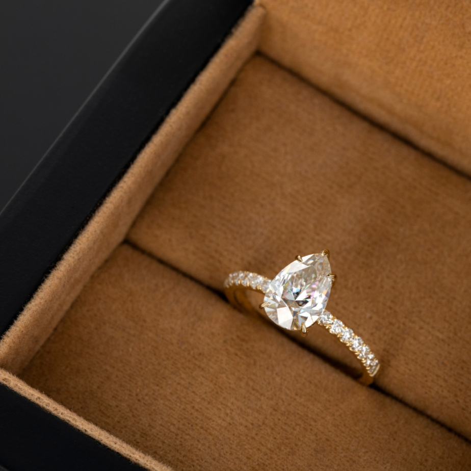 Pear-shaped diamond ring in a black and brown ring box.