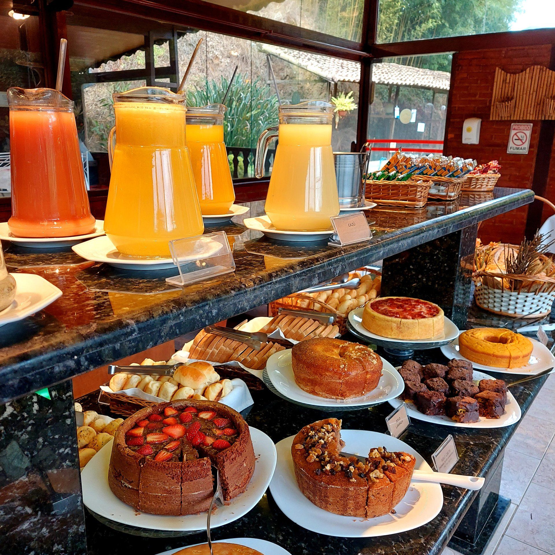 Buffet com sucos de frutas, bolos e doces.