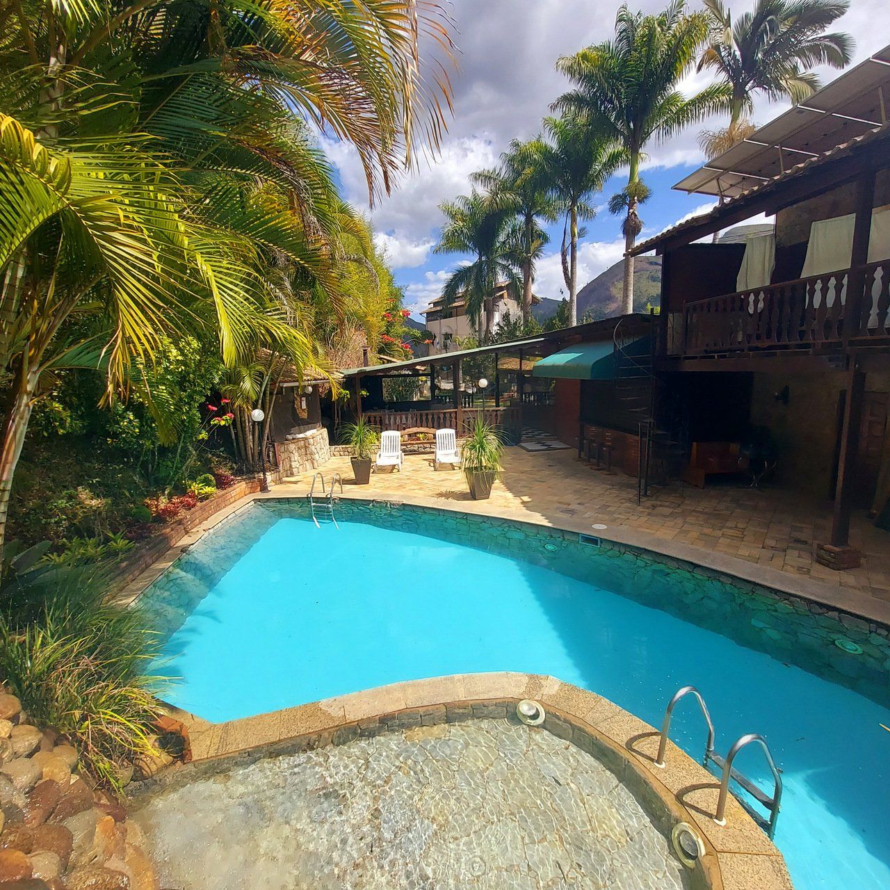 Piscina e spa em um resort tropical com palmeiras e um edifício.