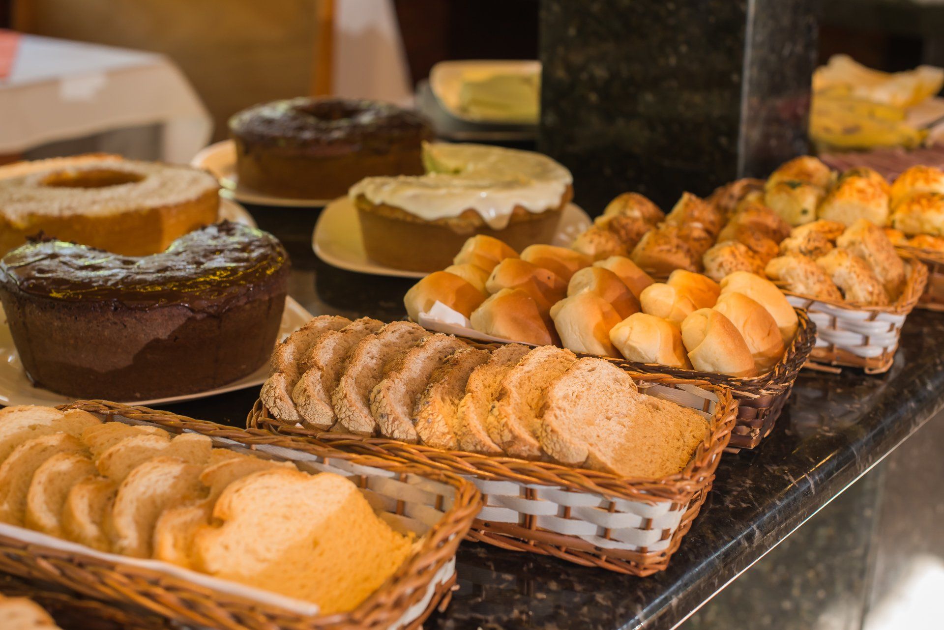 Uma mesa de bufê exibindo diversos pães e bolos.
