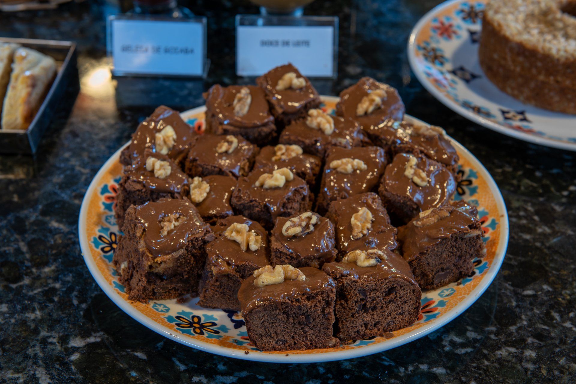 Brownies de chocolate com cobertura de nozes em um prato estampado, em um buffet.