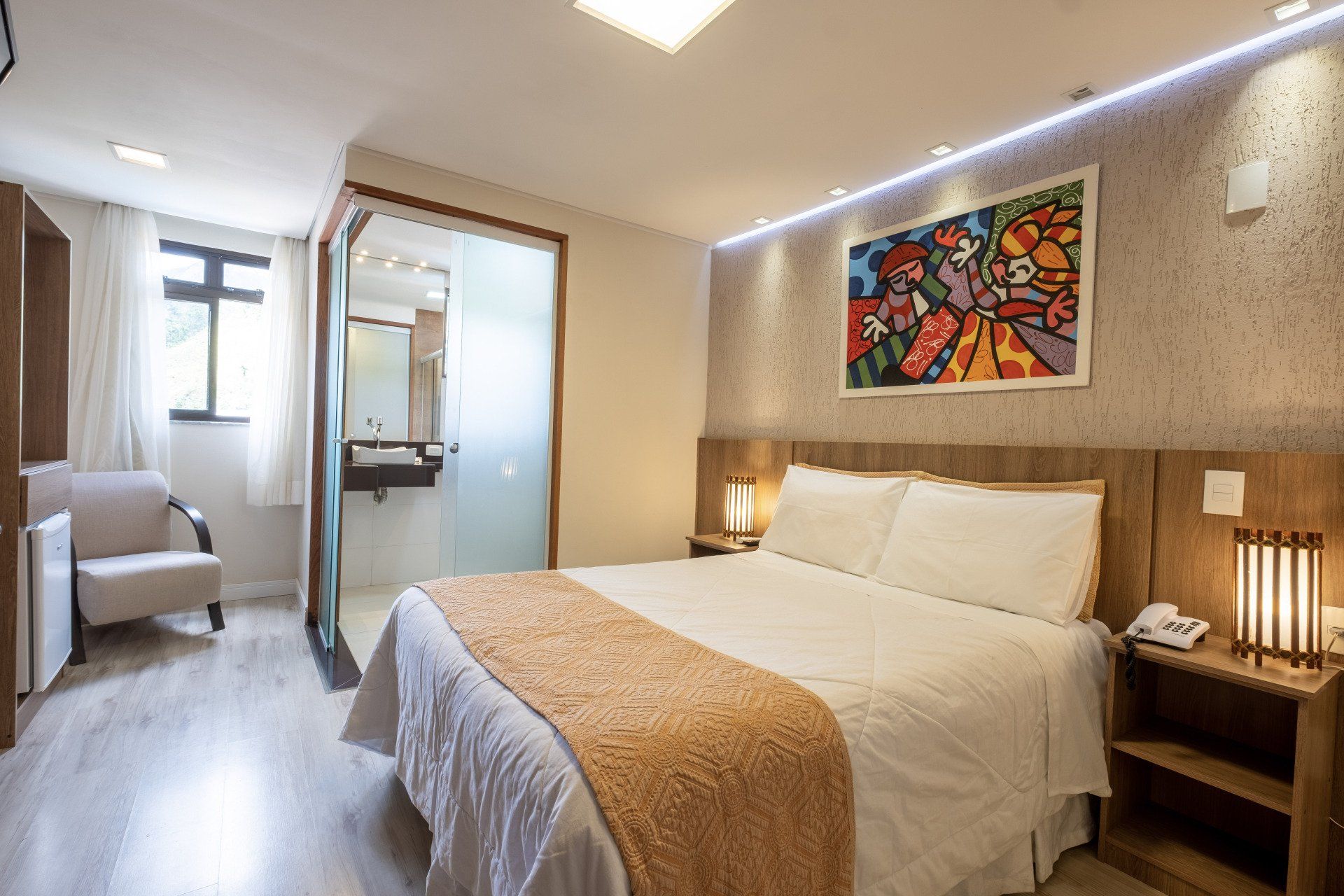 Quarto de hotel com cama, obras de arte e banheiro privativo.