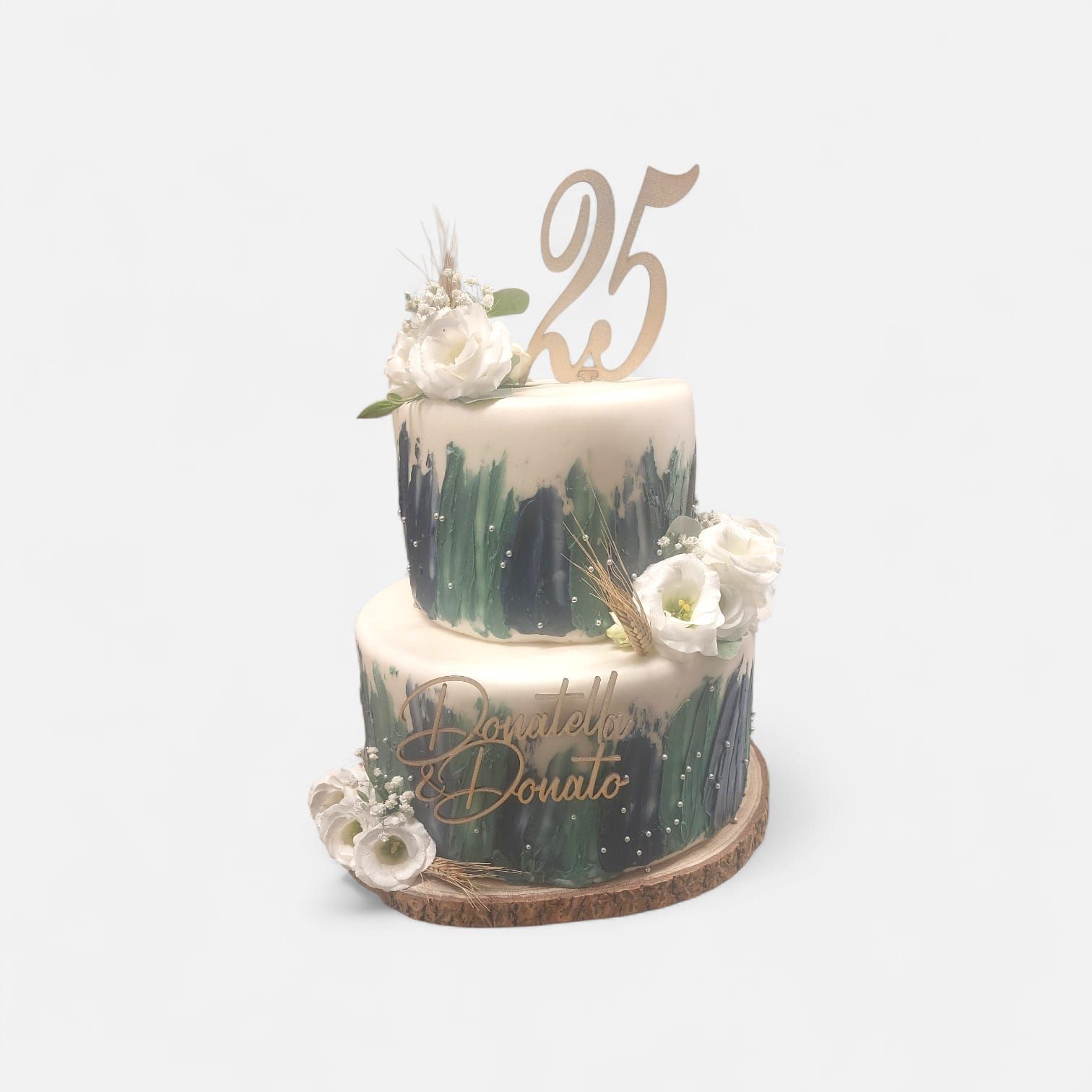 Torta a due piani con glassa bianca, pennellate color verde acqua e fiori bianchi. Topper dorato con la scritta