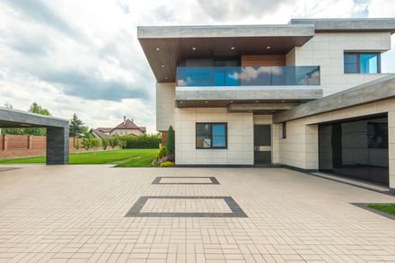 A large modern house with a large driveway in front of it.