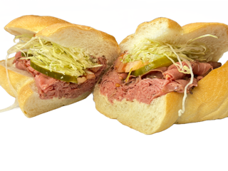 Two halves of a pastrami sandwich with lettuce and pickles