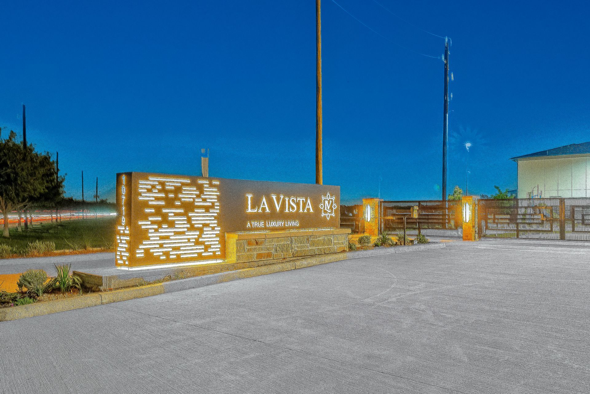 Stone entrance sign reading “LAVITA” beside a gravel road under a clear blue sky.