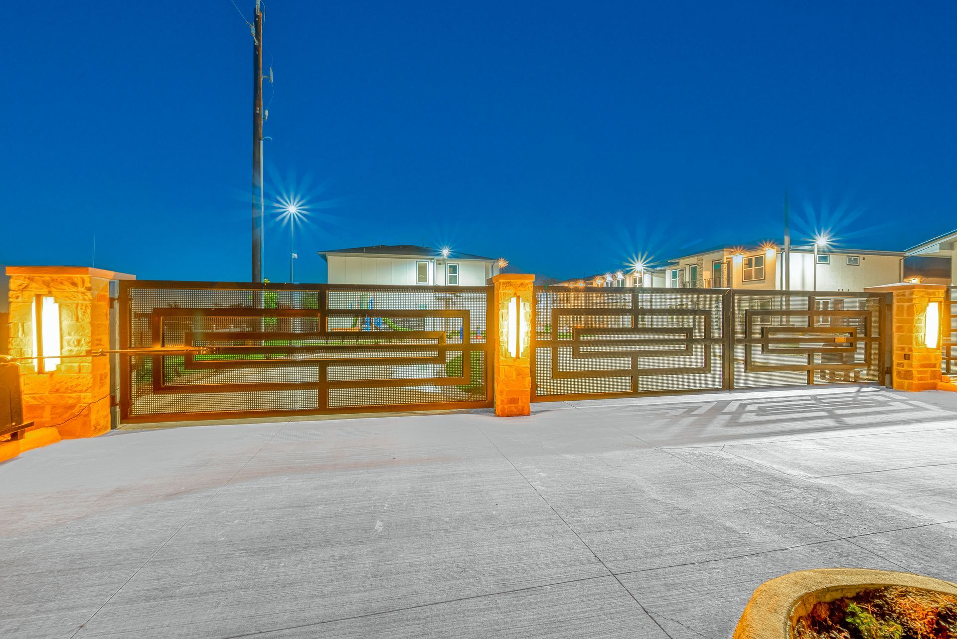 Snow-covered gated entrance with orange-lit pillars at night under a blue sky