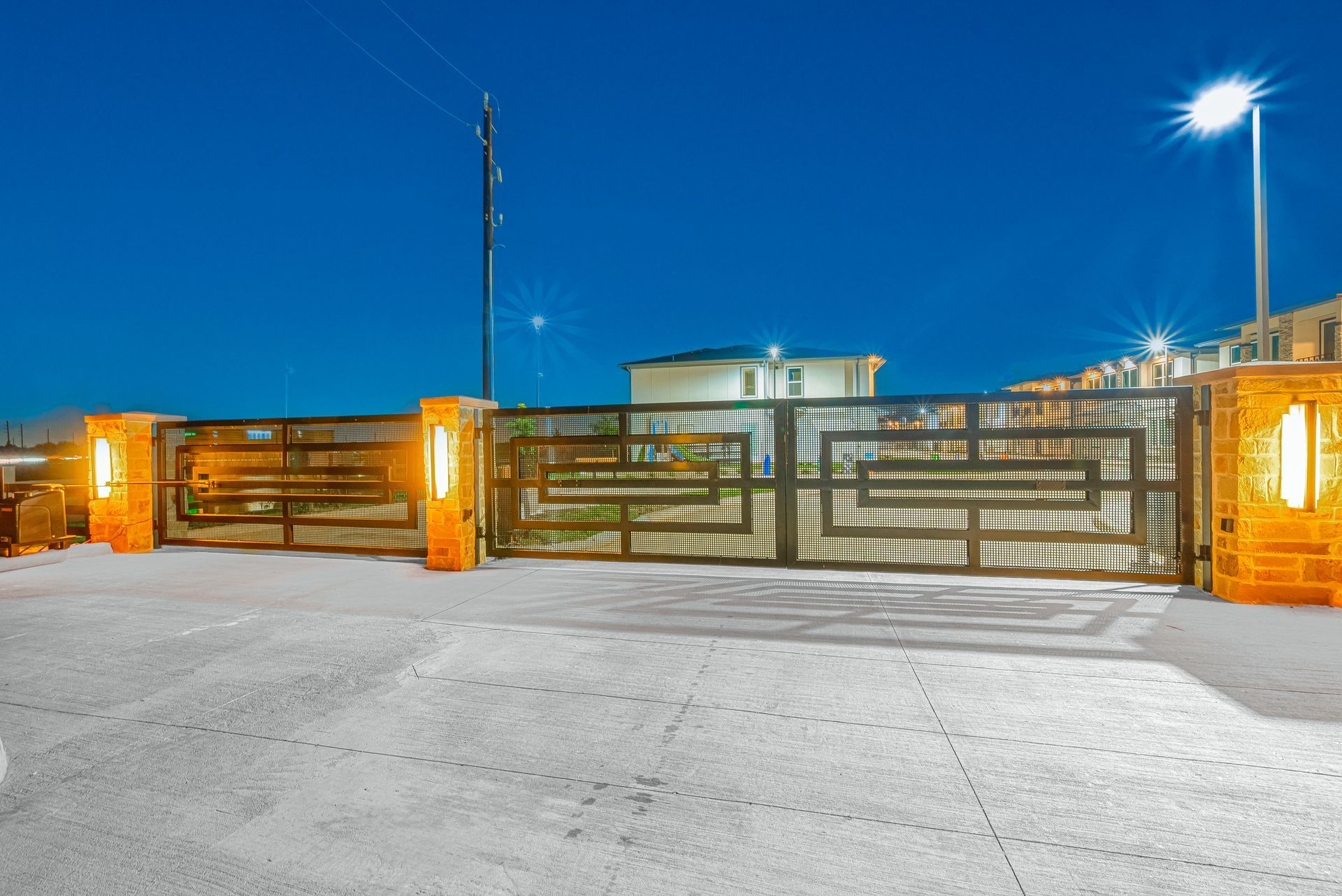 Closed metal gate at night with bright lights and snowy ground