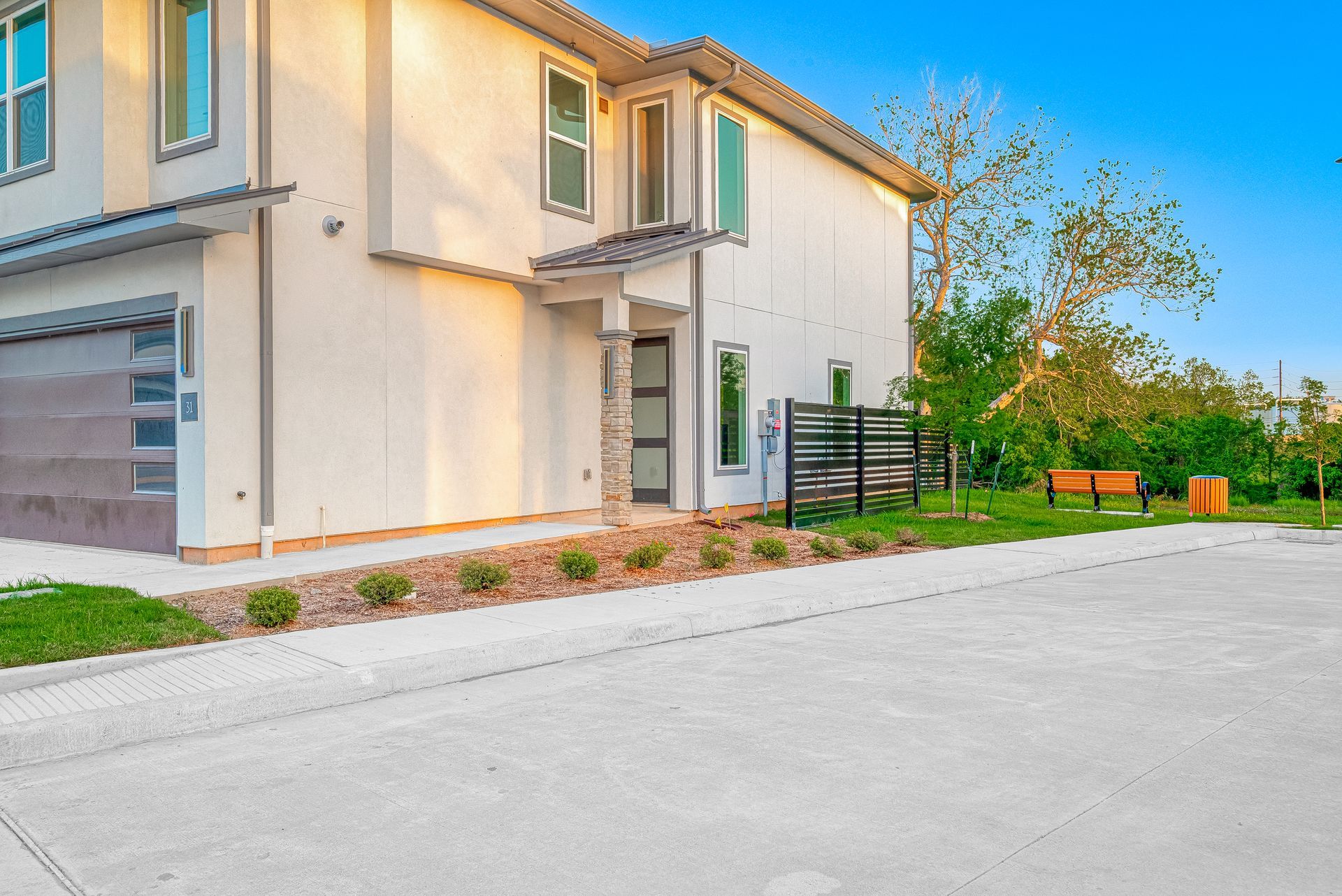 Modern beige house exterior with garage, front walkway, and small landscaped yard at sunset