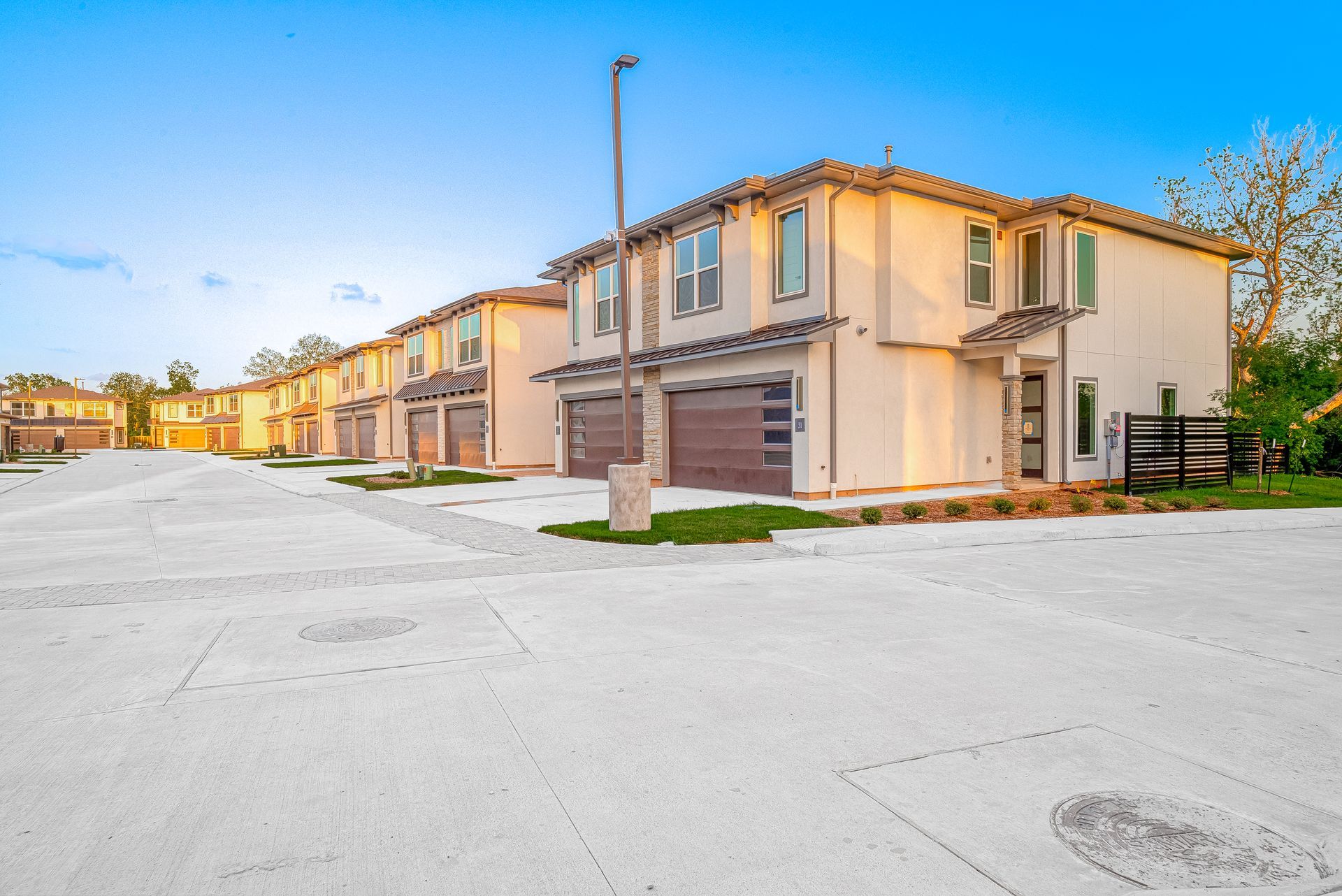 Row of beige townhouses on a snowy suburban street under a clear blue sky