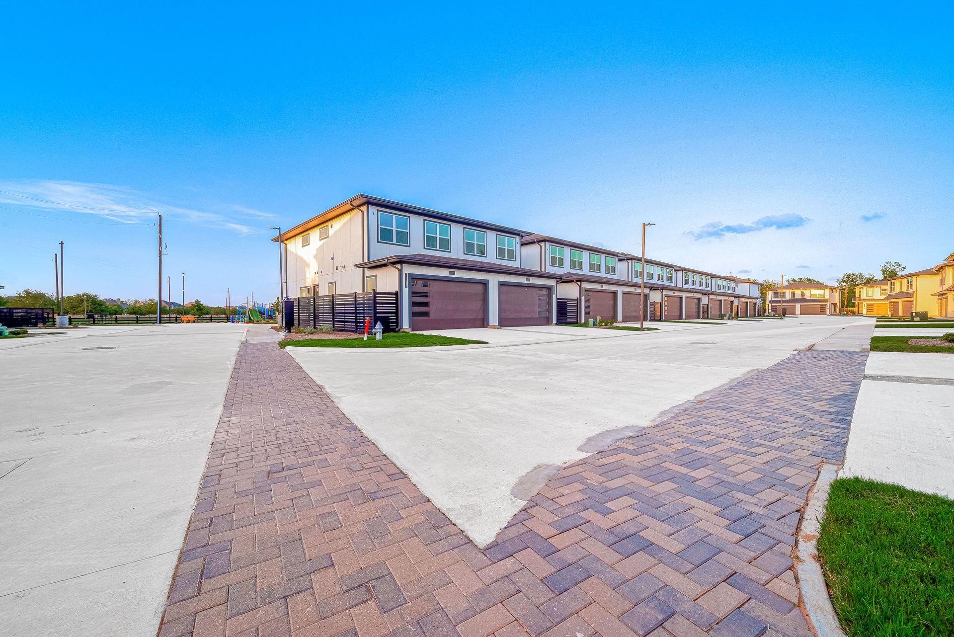 Brick apartment buildings beside a wide paved courtyard under a clear blue sky