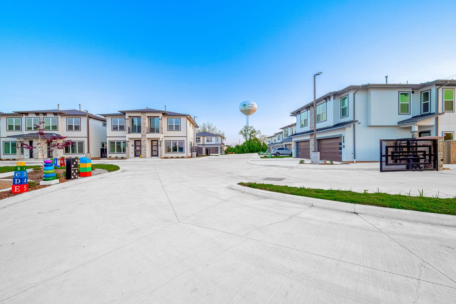 Colorful beachfront cottages around a wide paved courtyard under a clear sky