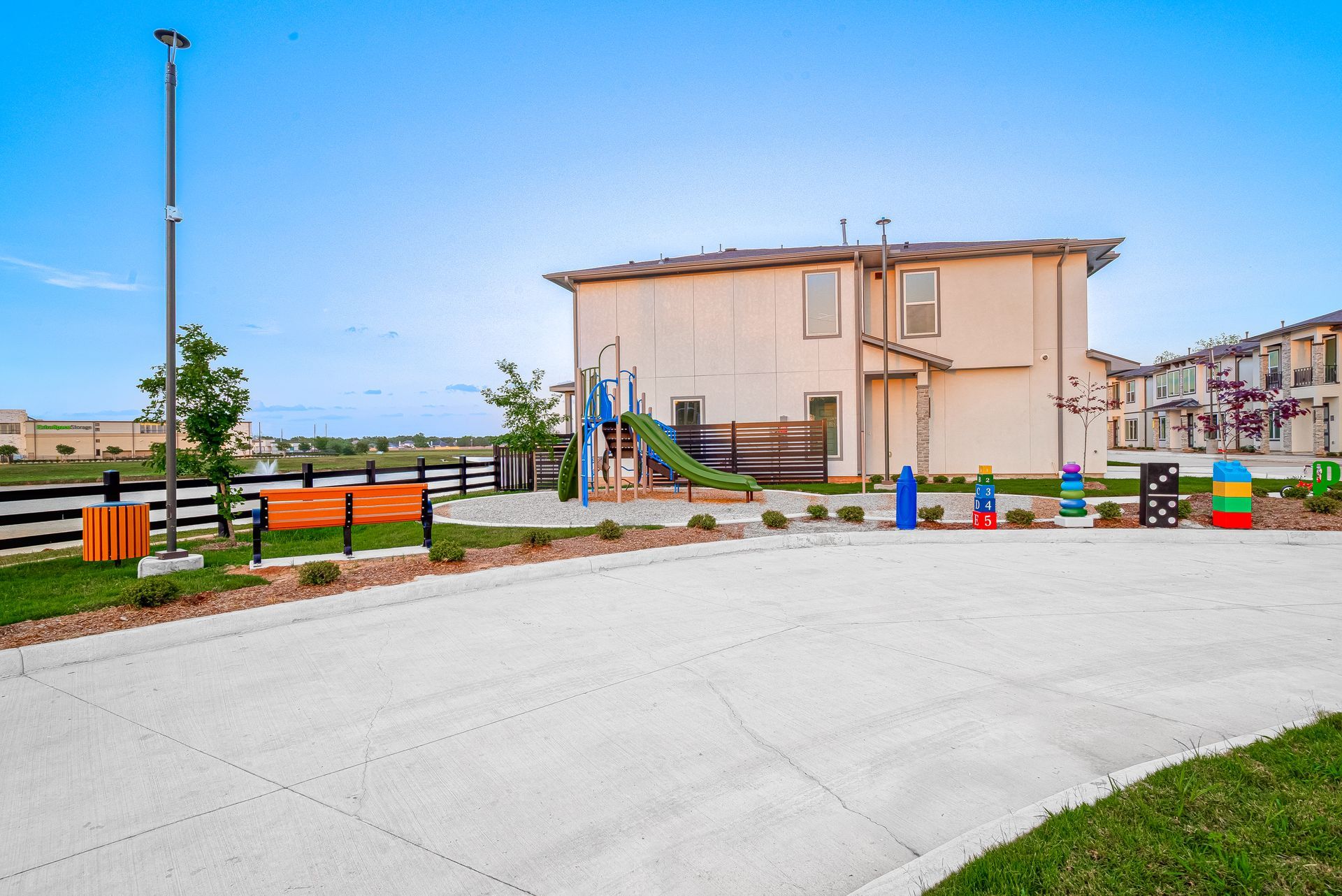 Apartment complex playground with colorful equipment beside a paved walkway on a sunny day