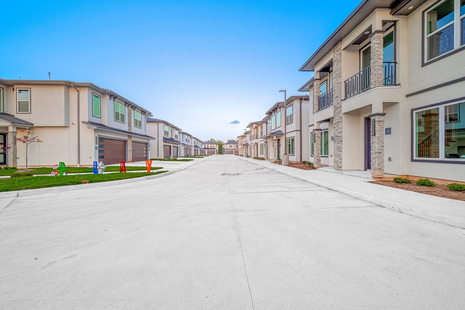 New suburban street lined with modern townhouses under a blue sky