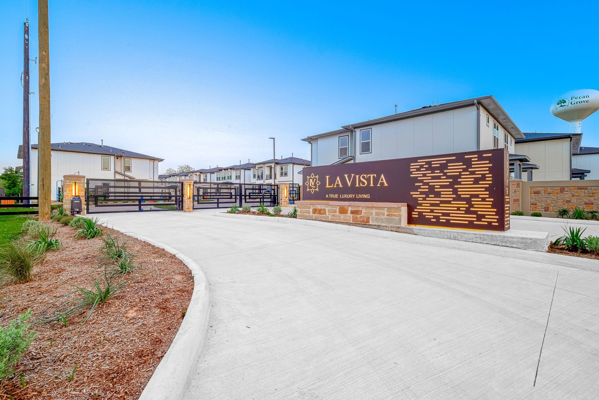 Entrance to La Vista community with stone sign, paved drive, and desert landscaping