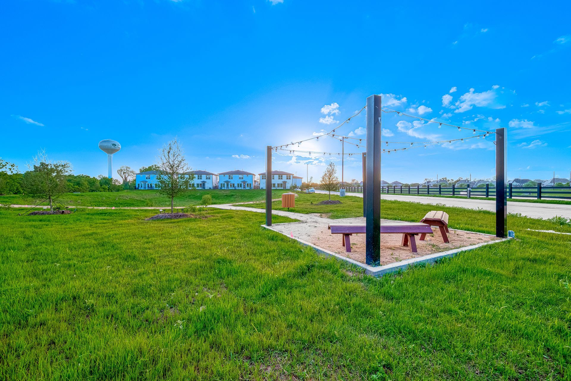 Outdoor fitness area with benches and pull-up bars on a grassy field under a bright blue sky