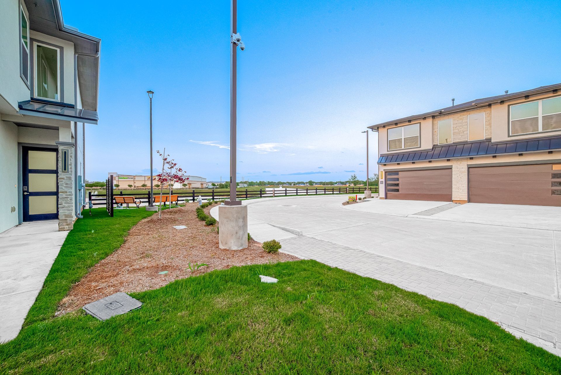 Modern apartment complex courtyard with grass, concrete paths, and a blue sky