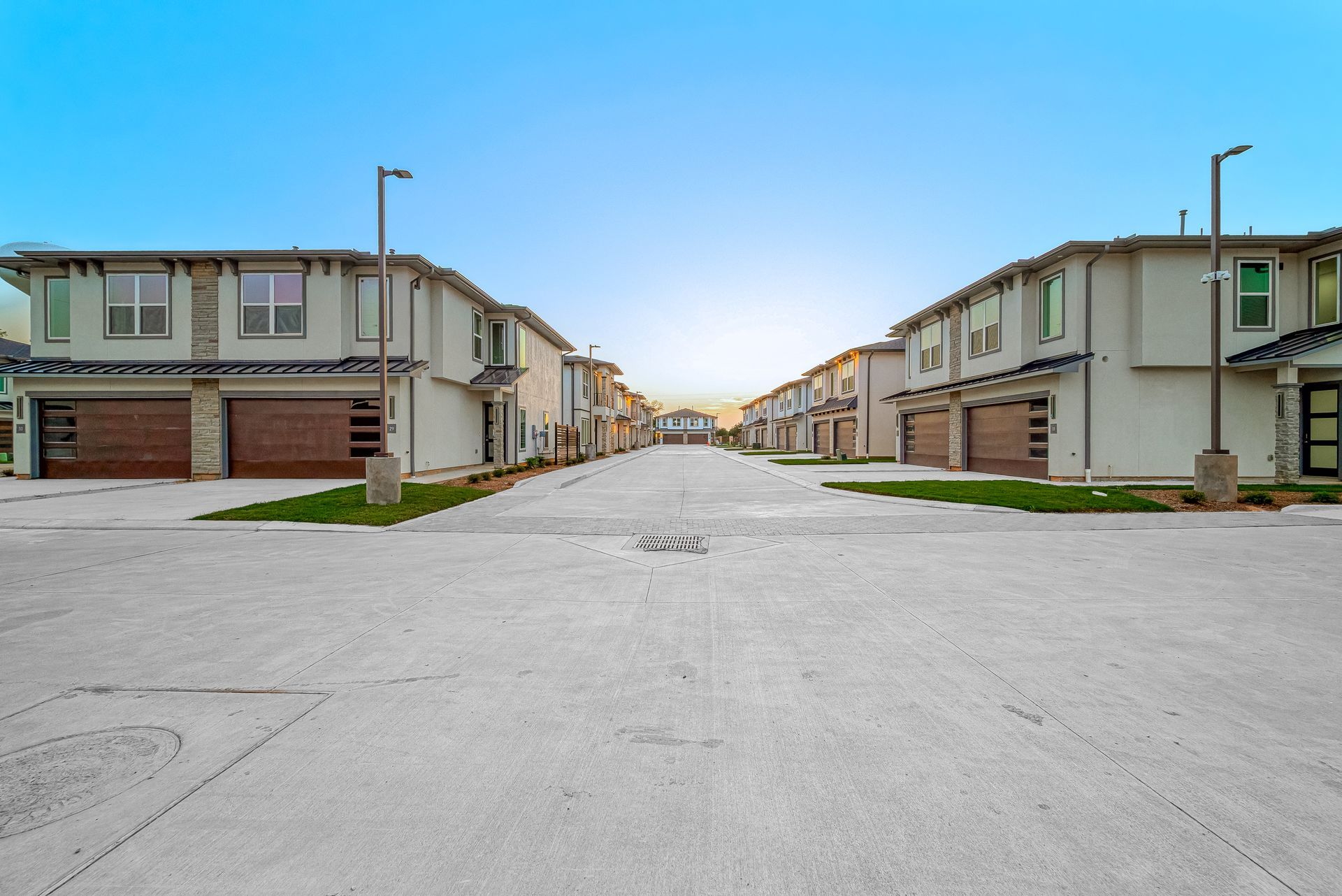 Empty apartment complex driveway between rows of beige townhouses on a sunny day