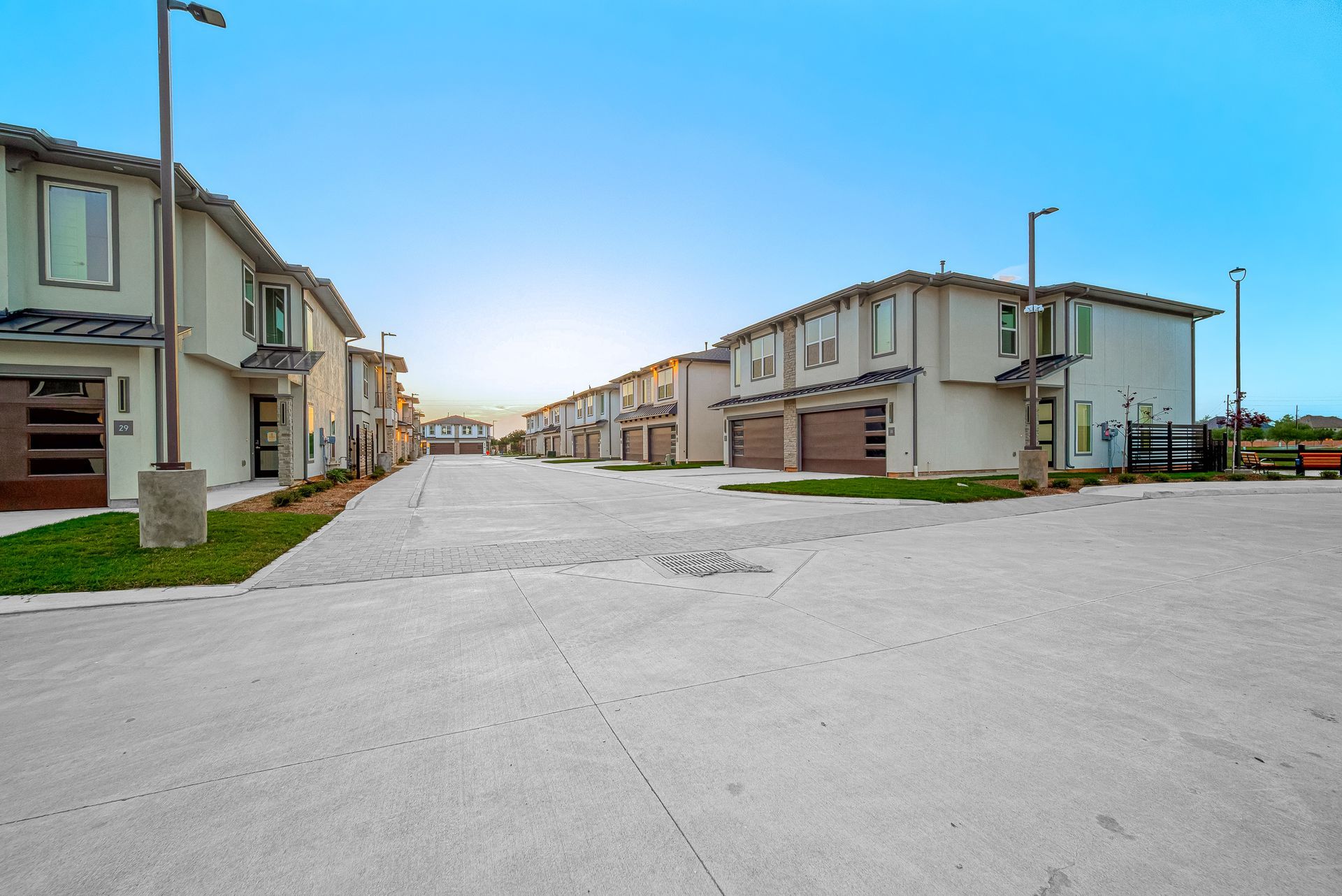 New residential street with modern houses and a wide paved road under a clear blue sky