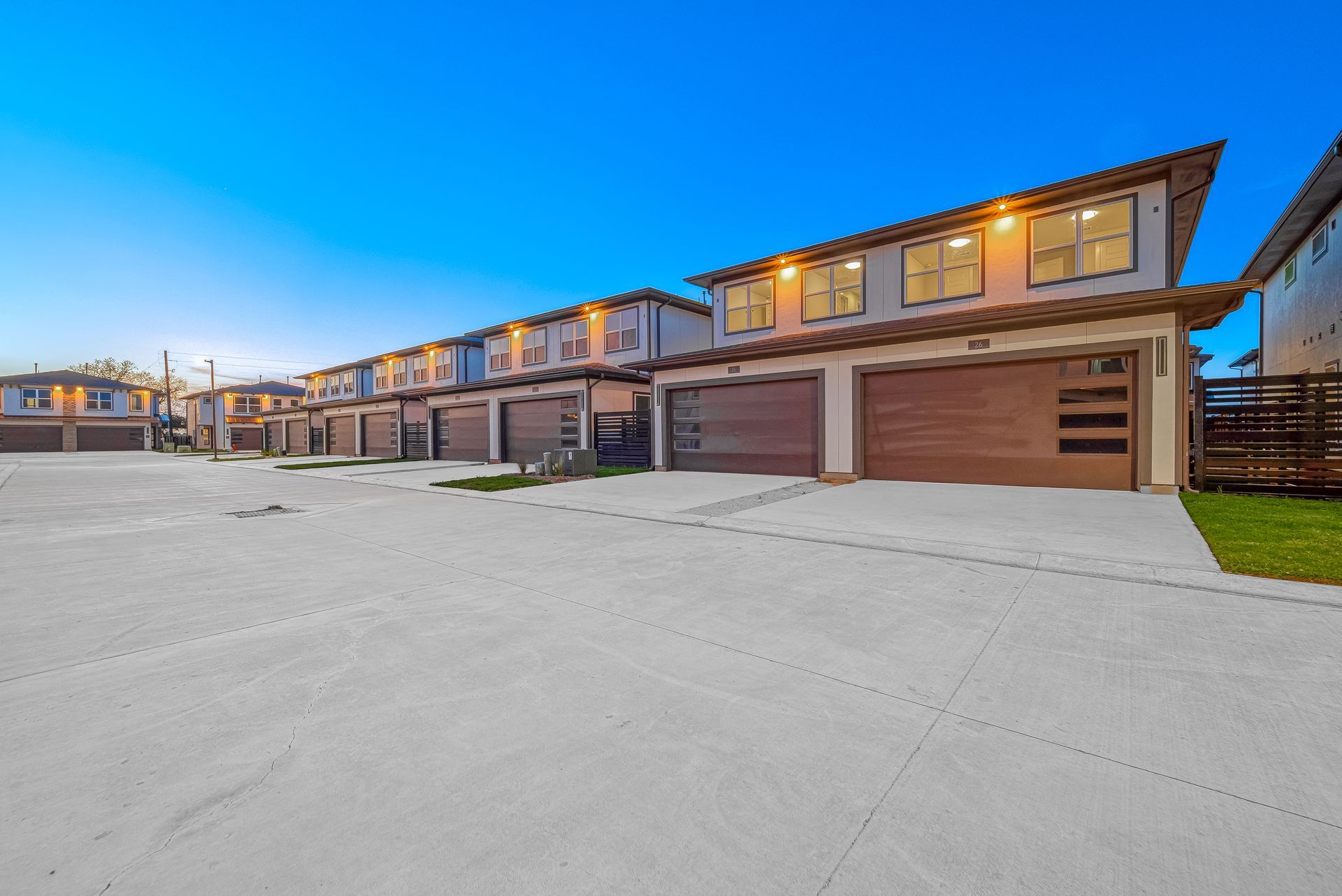 Snow-covered row of modern townhouses with attached garages at dusk