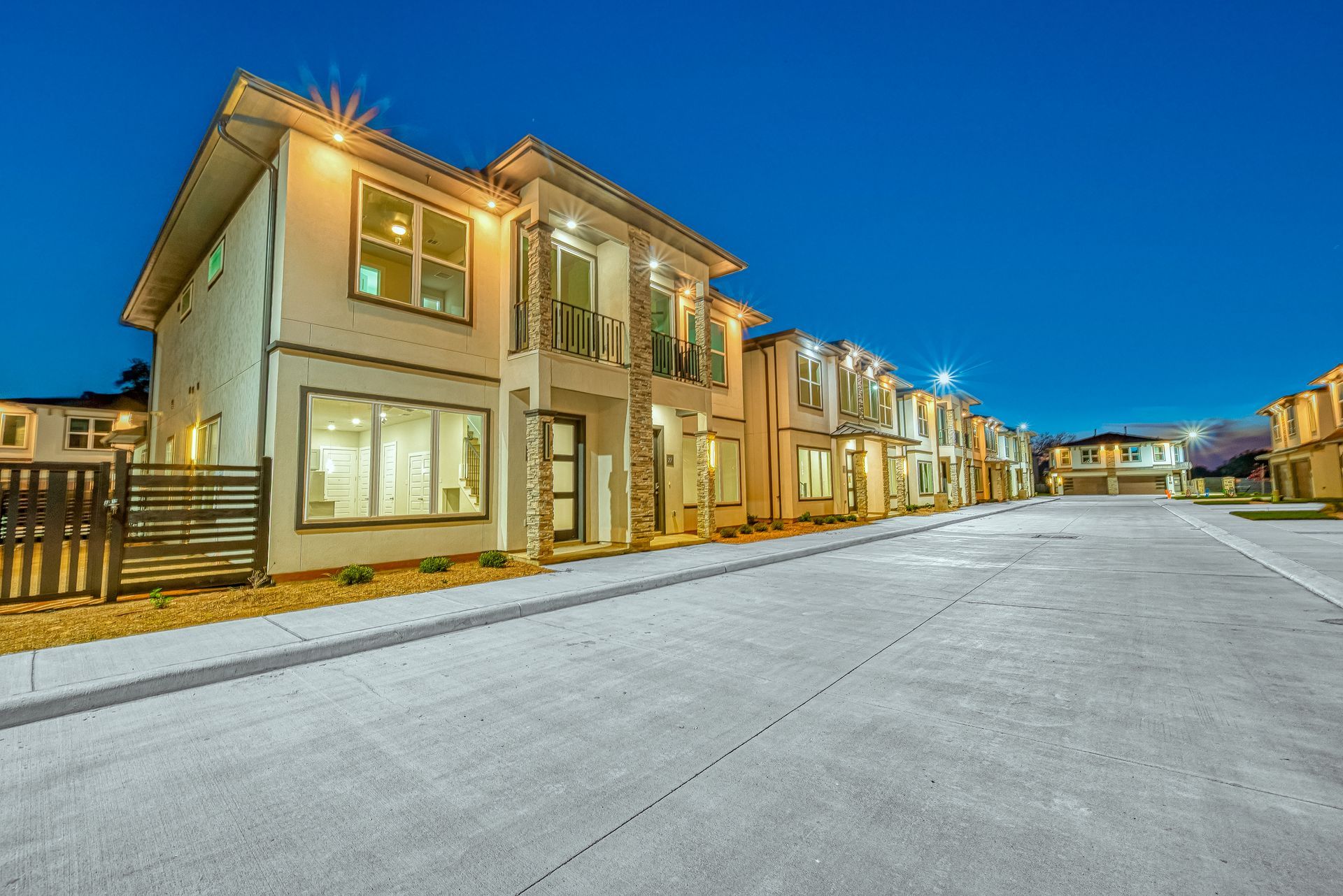Row of modern townhouses along a wide empty street at dusk